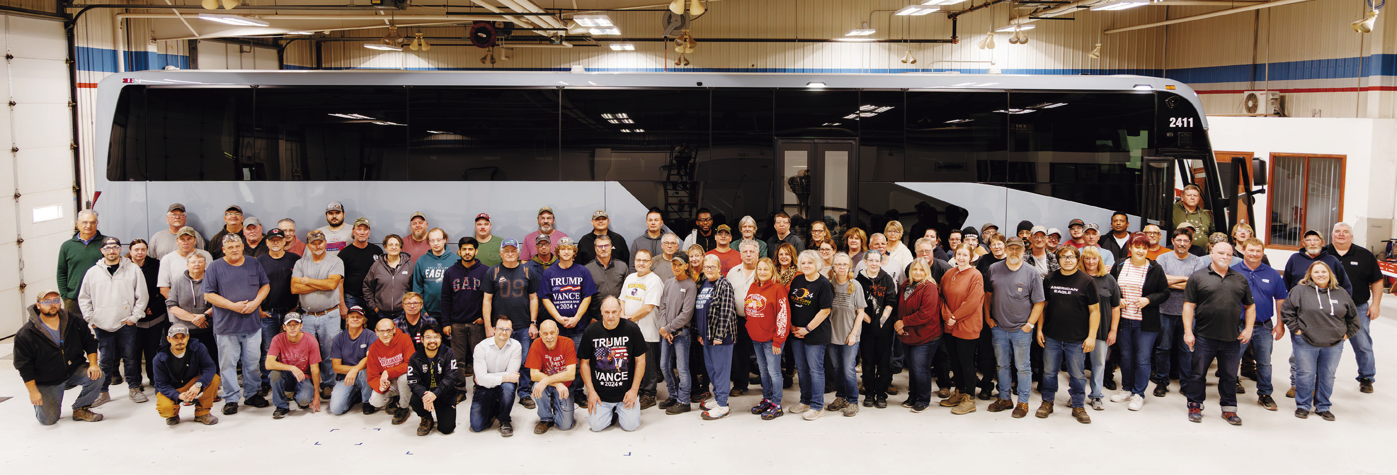 The MCI Pembina team pose in front of their first electric coach assembled at the plant.