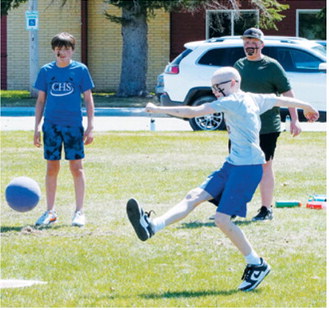 Chet Ottem follows through on a kick as classmates look on during the sixth grade vs. teachers kickball game held to wrap up the school year. Photo by Larry Stokke