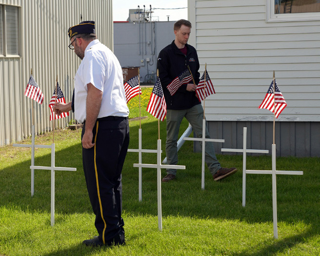 Commander Scott Anderson (left) places flags atop crosses along with Alan Hiltner (right). Alan, Adjunct Leon Hiltner’s son, is a member of the Sons of the American Legion. Photo by Larry Stokke.