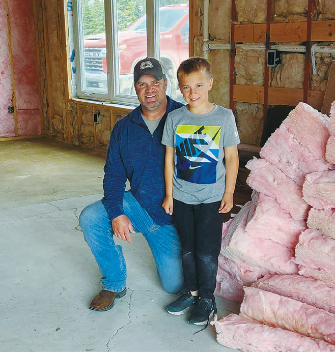Brock Mitchell with his youngest son, Cruz, were busy tearing out insulation on July 2. Photo by Hilary Nowatzki.