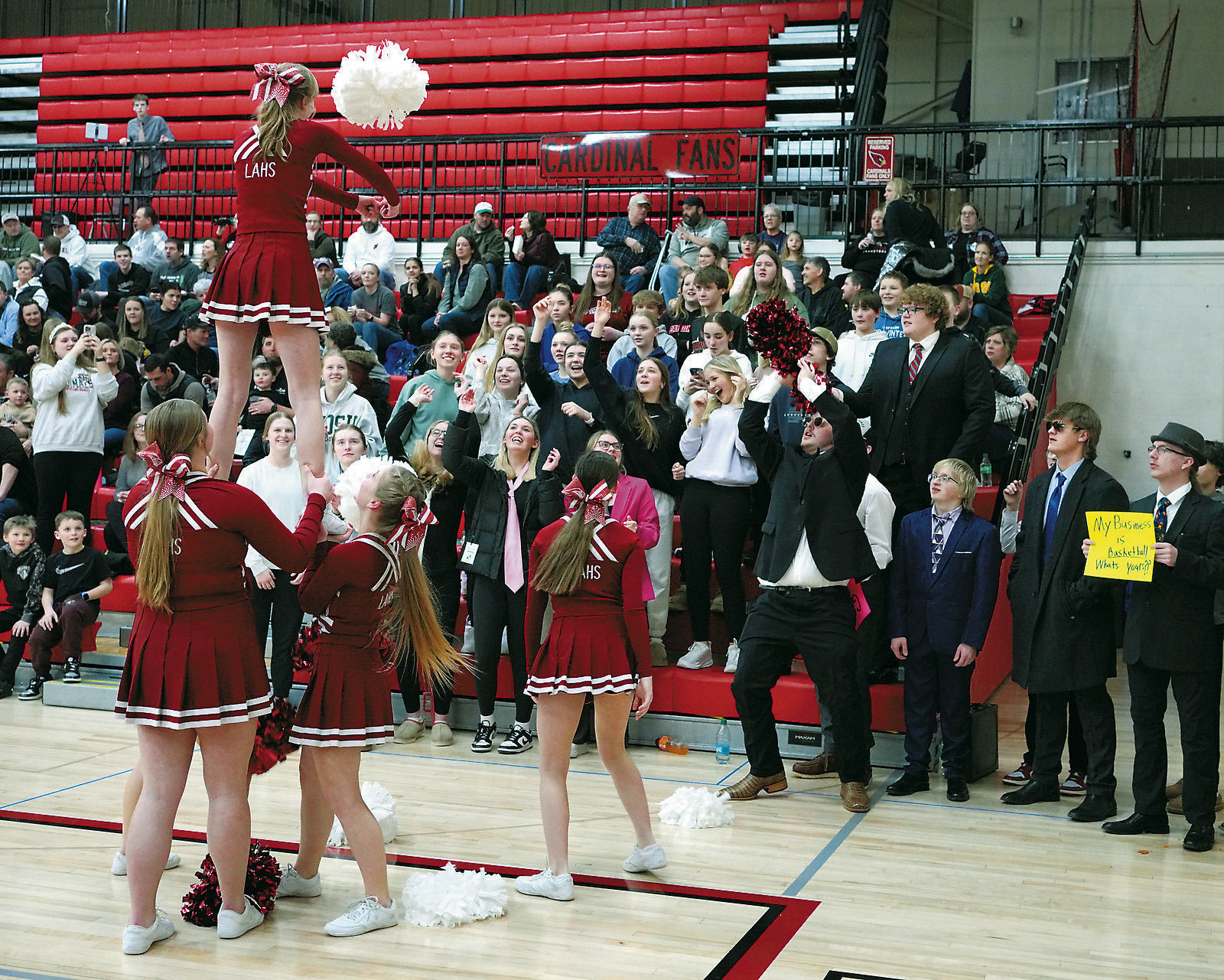 The Cardinal Cheer Team kept the fans entertained with an impromptu game of shooting baskets with pom poms. Photo by Larry Stokke.