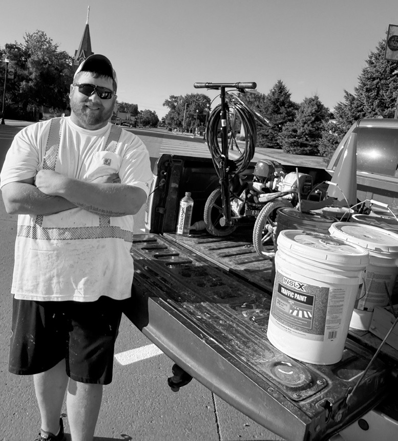 Nate the PMT posing with his Titan PowerLiner 850 line sprayer machine and pails of paint.