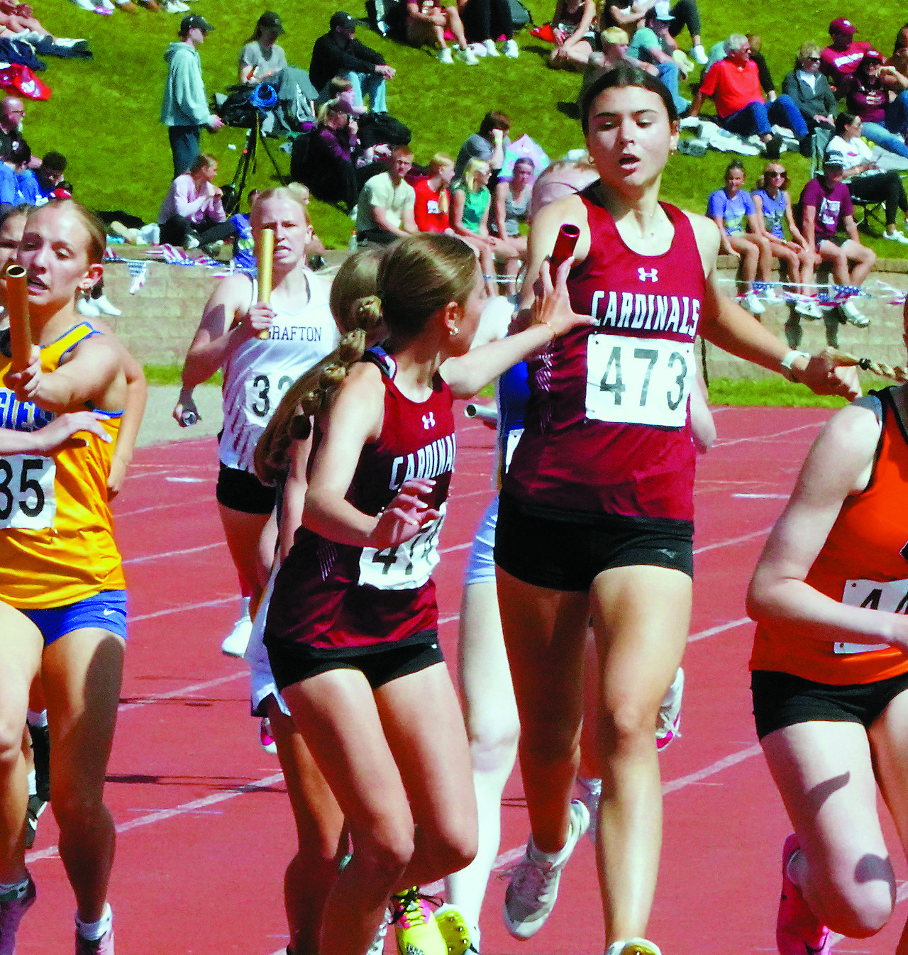 Taya Feist hands the baton to Meggy Hetletved who, along with teammates Hallie Overby and Mya Swanson, had their season best time in the 1600 meter run of 4:12.43. Photo by Larry Stokke.