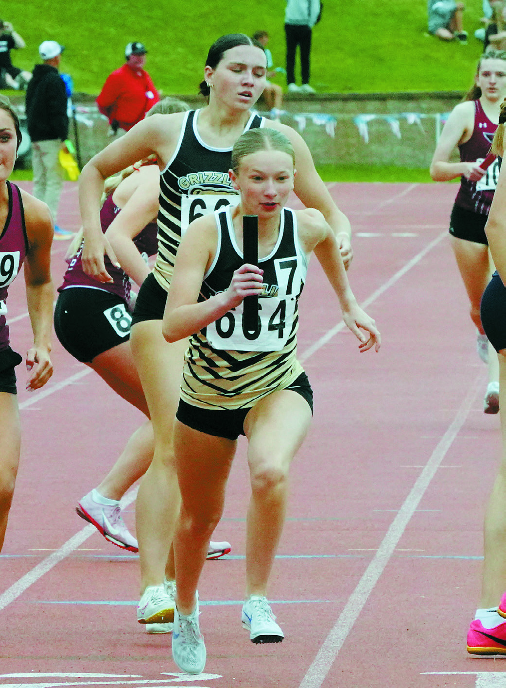 Emerson Helgoe takes the baton from Delaney Denault and heads off on the final leg of the relay. Photo by Larry Stokke.