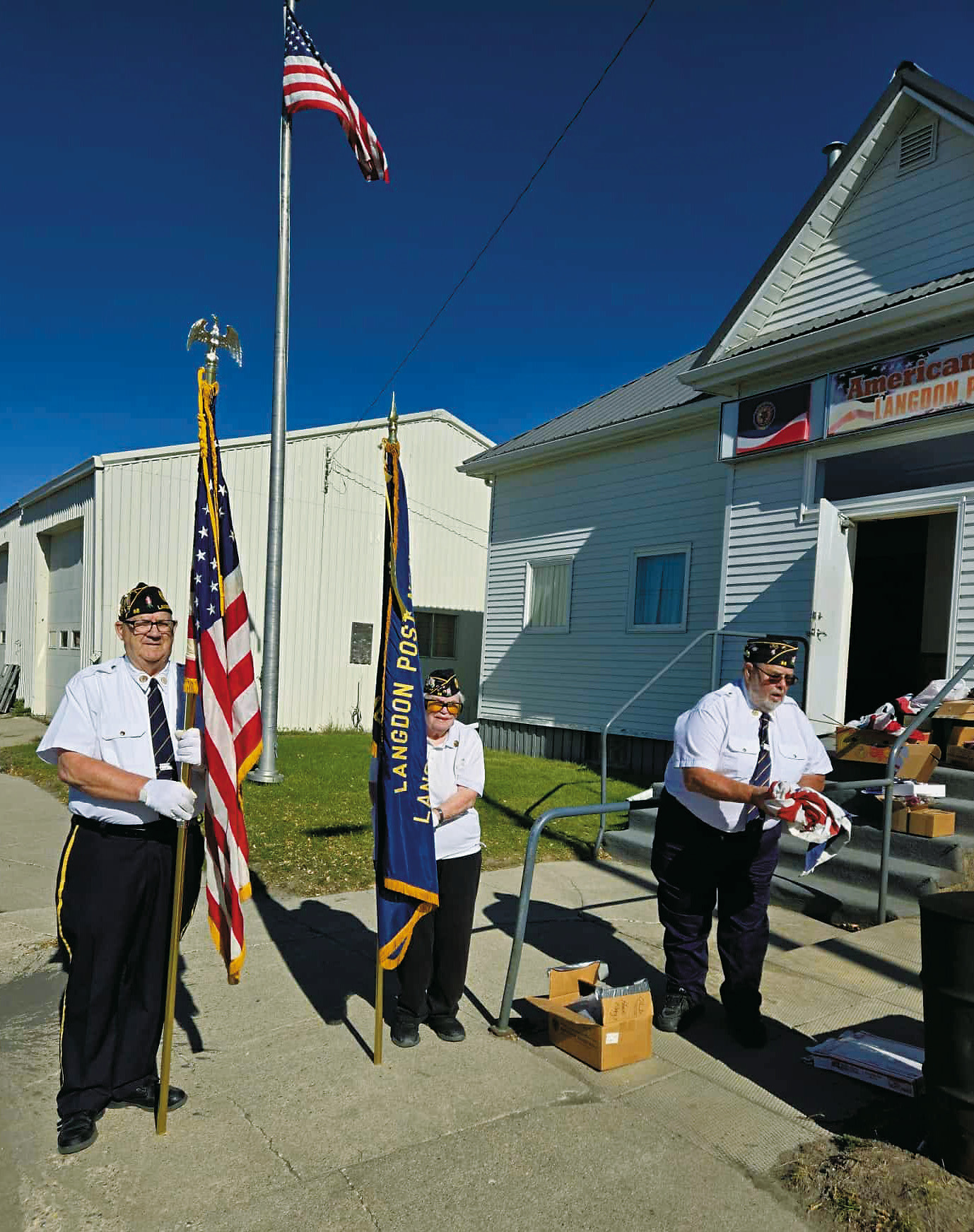 After a brief ceremony, Langdon American Legion Post 98 members honorably disposed of worn, tattered, and faded American flags last week. Daryl Kempel (left) and Anna Spivey (middle) stood as Honor Guards while Dennis Hansel (right) prepared a U.S. flag for burning.