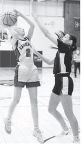 Mya Swanson drops in a basket with a Thompson Tommie guarding her. Photo by Larry Stokke.