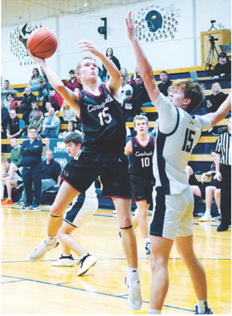 Caleb McDonald eyes the basket and puts up a shot over Garret Willits in Walhalla on Jan. 13. Photo by Larry Stokke.