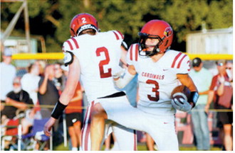 Langdon Area-Munich’s TJ Henderson, No. 3, celebrates with teammate Eastyn Schaefer, No. 2, during the Cardinals’ game against the Oakes Tornadoes on Friday, Aug. 21, in Oakes. Photo by Larry Stokke