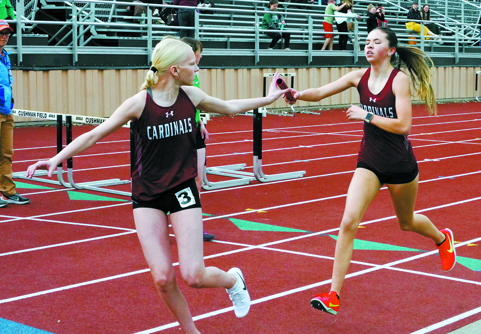 Olivia Lorenz hands the baton to Mya Swanson who, along with teammates Aubrey Badding and Hallie Overby, took 1st place in the 4x800 meter relay with a state qualifying time. Photo by Larry Stokke.