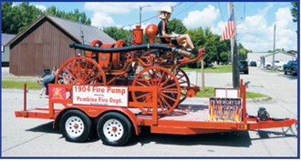 A restored 1904 fire pump owned by the Pembina Fire Department rolls through the Pembina Fourth of July parade. The historic piece served as a tribute to the department's history and the firefighters who have served the community through the years. Photo by Larry Stokke