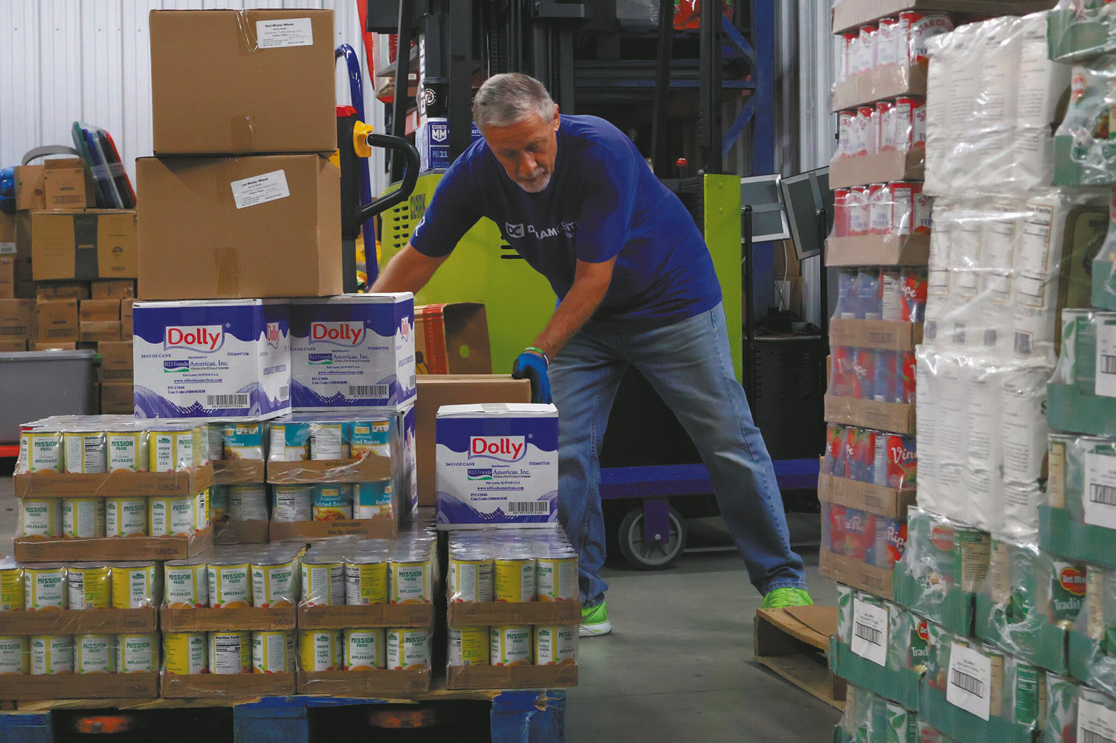 John Hoffman, a volunteer at the Dream Center in Bismarck, moves boxes of food from a pallet to a shelf in the facility storage area on Aug. 5, 2026. (Photo by Michael Achterling/North Dakota Monitor)