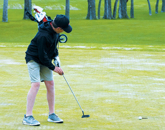 The Cardinals Ryder Moser sinks a putt and finishes the round with a score of 77, qualifying him for the State Meet. Photo by Larry Stokke.
