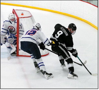 Ryland Peterson brings the puck around the back of the net under pressure from a Richland defender. Photo by Larry Stokke.