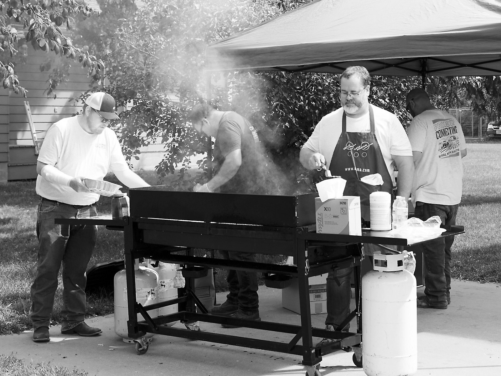 United Communications workers attending to the grill at their free luncheon last week. Photo by Larry Stokke.