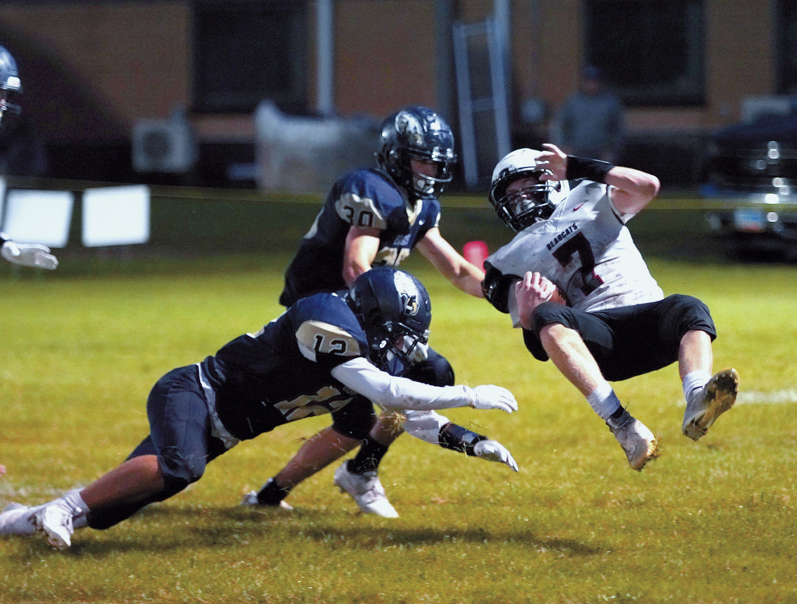 Weston Cosley sweeps the legs out from under the Bearcat's Sean Freund for a turnover in downs. Photo by Larry Stokke.