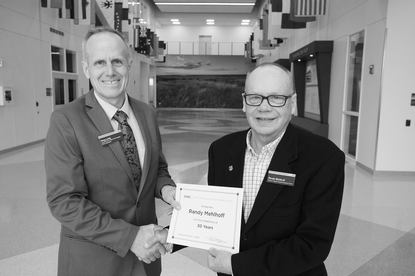 Randy Mehlhoff (30 years) receives congratulations from Greg Lardy. (NDSU photo)