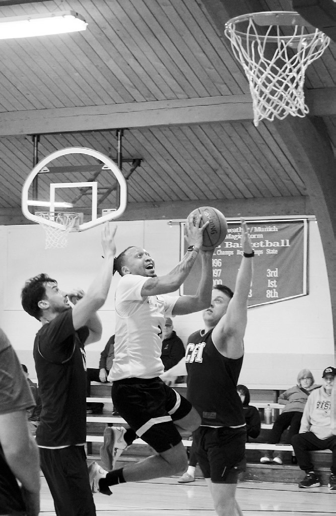 Jamal Willams slices between two defenders and lays in a basket. Photo by Larry Stokke.