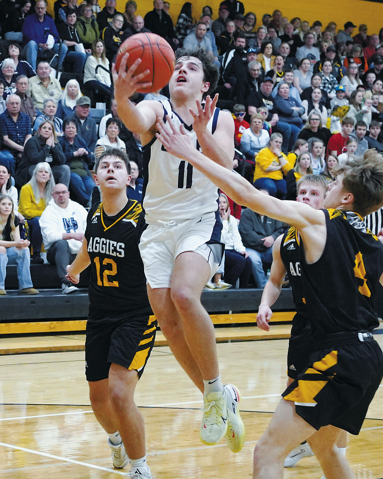 Grant Cosley eyes the basket, splits the Aggie defenders, and adds two points to the Eagles' score. Photo by Larry Stokke.