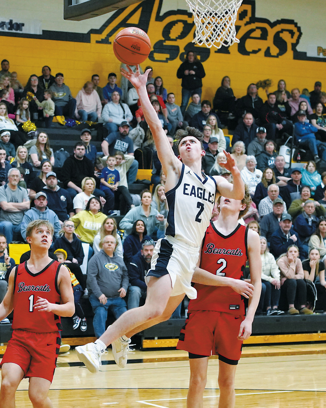 Kaden Moore drives past two Bearcats and drops in a layup. Photo by Larry Stokke.