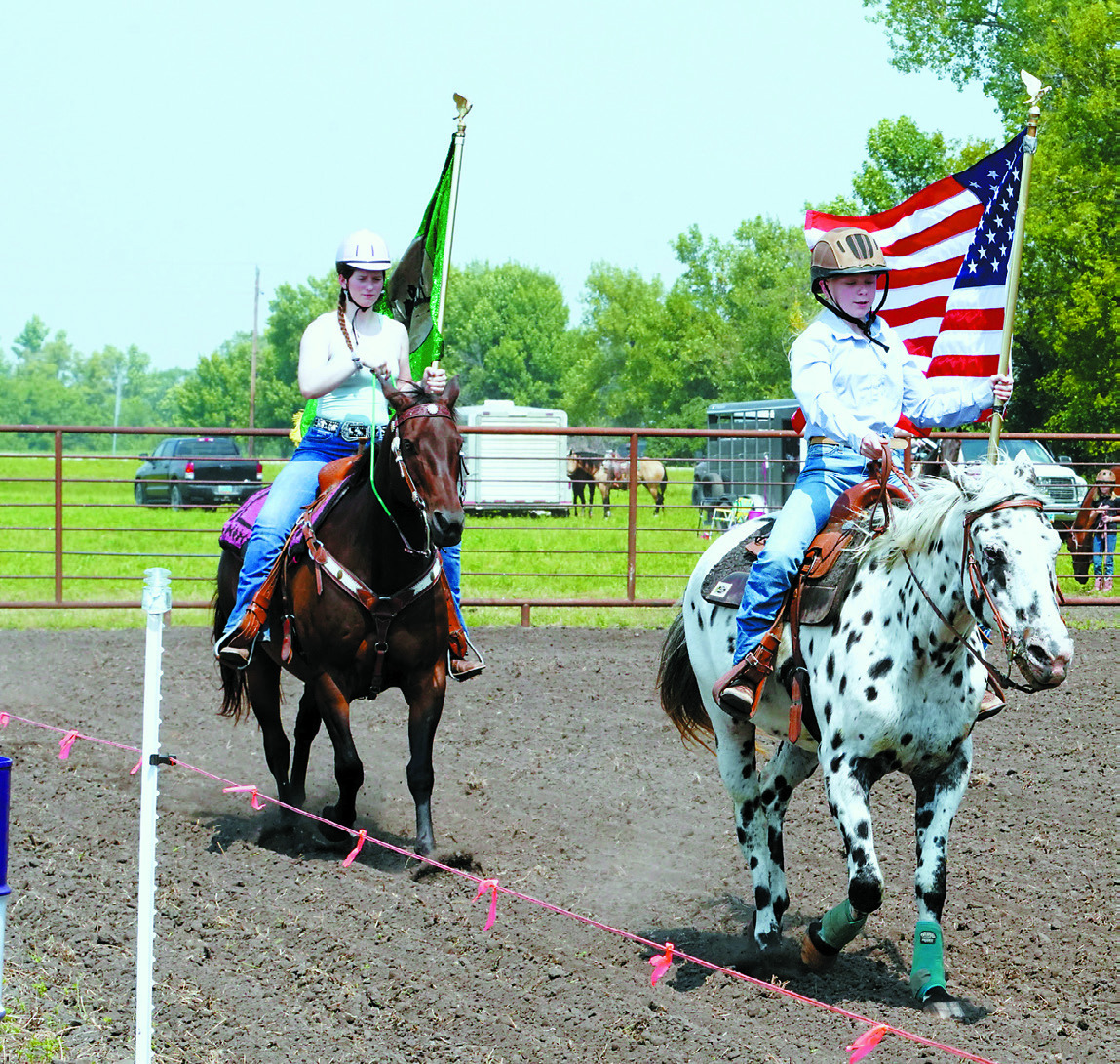 Carrying the American flag is Monica Bina on Dottie and following her is Ingrid Myrdal on Rudy. Photo by Larry Stokke.