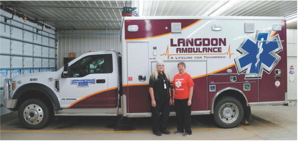 Lorraine Gage, left, and Sheila Beauchamp stand beside a Langdon Ambulance Service unit after being recognized by the National Registry of Emergency Medical Technicians for achieving 40 consecutive years of National EMS Certification. Photo by Larry Stokke