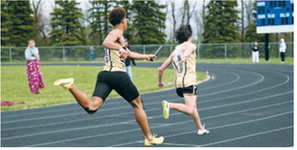 Trevor Hilluka-Moore hands the baton to Boone Carrier during the 4x200-meter relay at the regional meet. Hilluka-Moore, Carrier, Micah Dutch and Kylan Schafer placed third for the PCN Grizzlies. Photo by Ashley Schafer