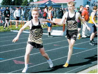 Owen Crosby hands the baton to Micah Crosby during the 4x800-meter relay at the regional meet. Other relay members were Ethan Kendel and Jaxon Suedel. Photo by Larry Stokke