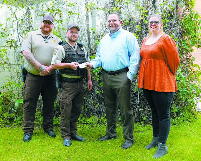 (L-R) Deputy Gabe Johnston, Sheriff Matt Wright, Pastor Burton Van Kirk of First Baptist Church and Anna Lill. Photo by Larry Stokke.