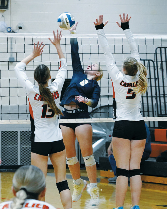 Kate Bjornstad sends the ball through two Tornadoes for a kill. Photo by Larry Stokke.