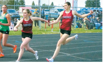 Ella Goodman receives the baton from Taya Feist during the 4x400-meter relay at the regional meet. Goodman, Feist, Hallie Overby and Olivia Lorenz placed second for the Langdon Area/ Munich Cardinals. Photo by Larry Stokke