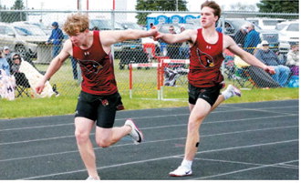 Braxton Lindseth takes the baton from Evan Ottem during the 4x200-meter relay at the regional meet. Lindseth, Ottem, Nathan Pengilly and Frashawn Kelso placed eighth for the Langdon Area/Munich Cardinals. Photo by Larry Stokke
