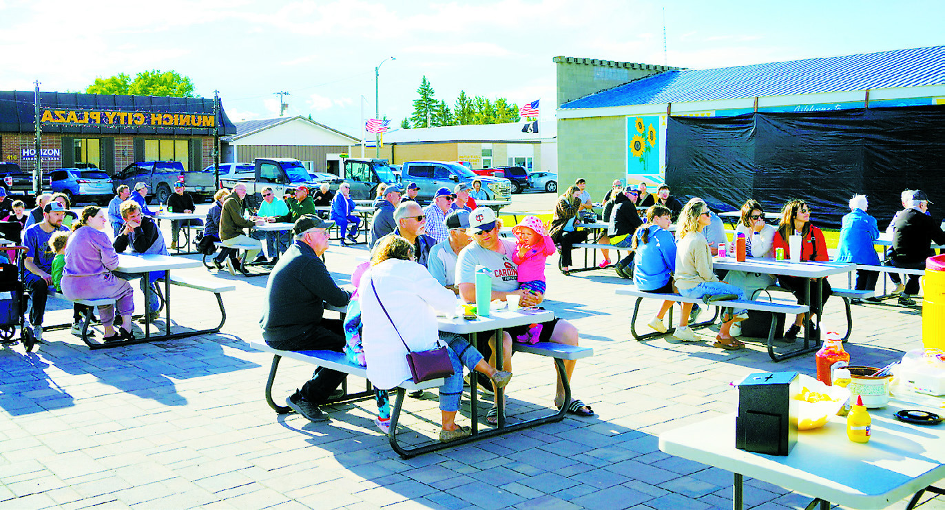 Community members gather at Munich City Plaza on June 24 for the unveiling of a new downtown mural celebrating the community's history, heritage and agricultural roots. Despite threatening weather throughout the day, residents turned out in force to celebrate the completion of the project. Photo by Larry Stokke.