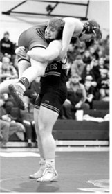 Senior Gavin Symington easily picks his opponent off the mat and pinned him to win both his matches by pin falls. Photo by Larry Stokke