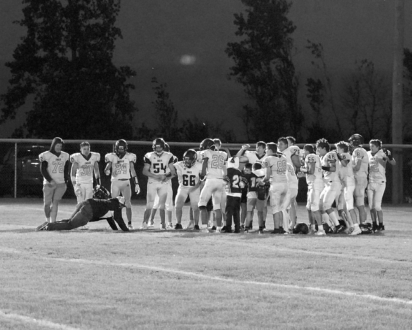 Bryce Hartje keeping up the traditional belly slide into the team meeting after a win over the Cougars in Rolla. Photo by Larry Stokke.