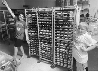 The owners' children lend a hand as racks of donuts are prepared ahead of Bread Pan Bakery's National Donut Day promotion. The bakery produced approximately 2,700 donuts for the event. Submitted photo