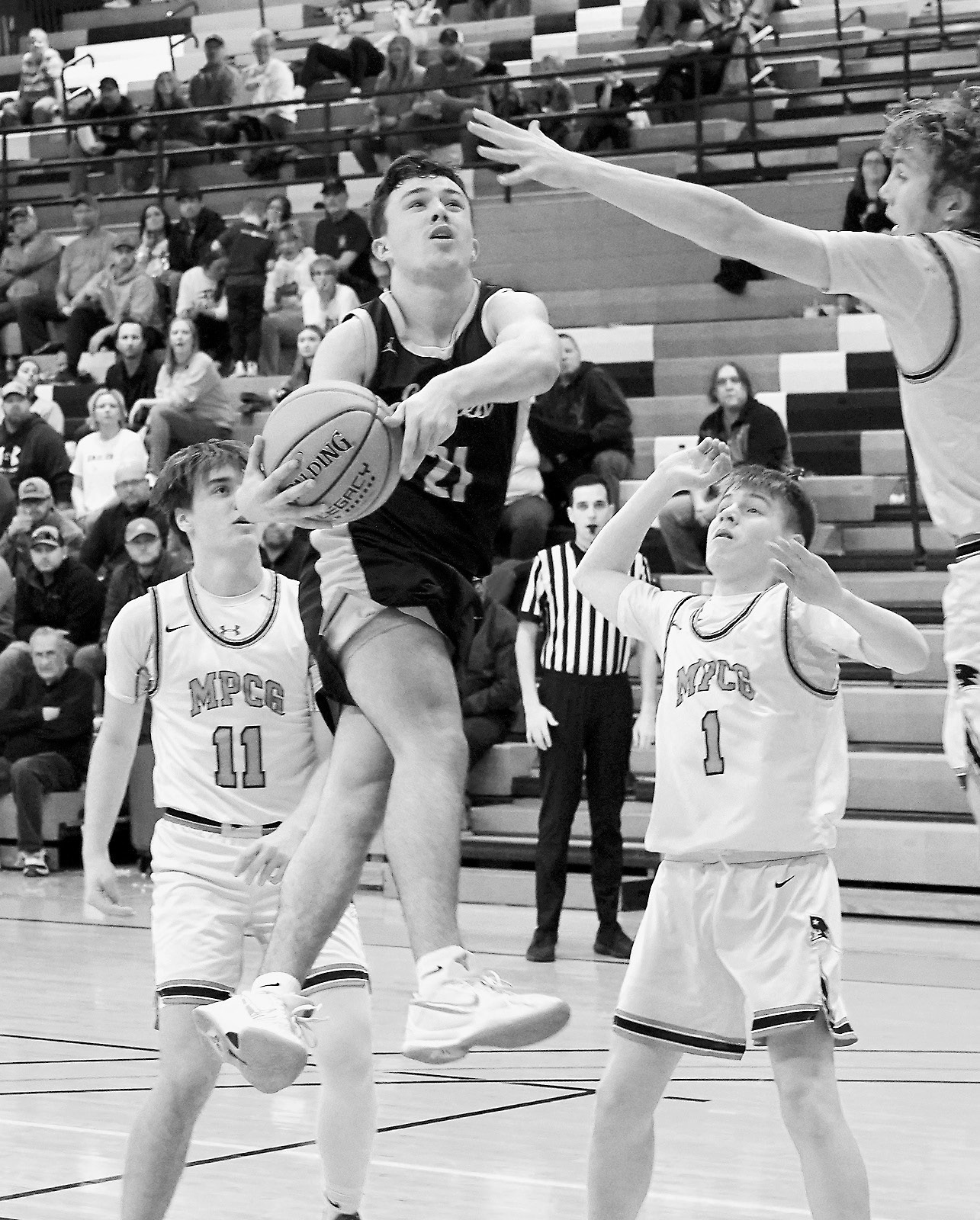 Player of the Game Brody Berg leaps high and drops one in a basket to finish the game with 17 points versus MPCG. Photo by Larry Stokke.