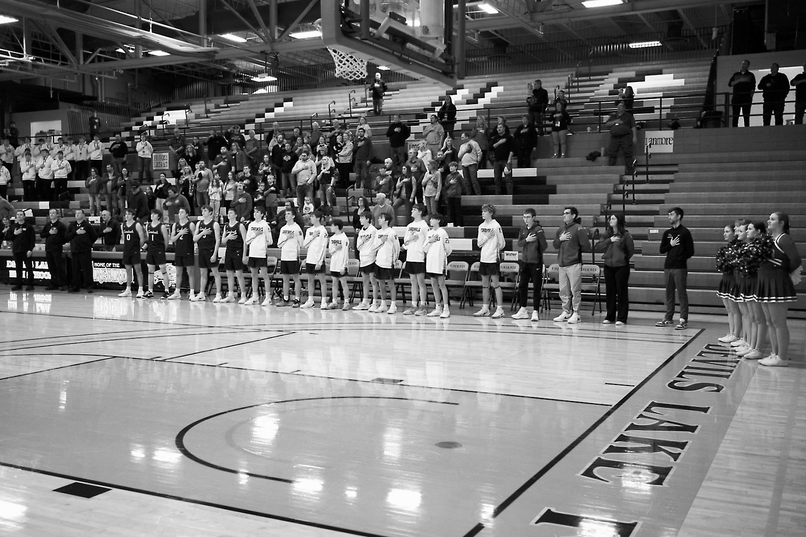 The Cardinal team and cheerleaders pay tribute to our flag at the start of the evening on March 10. Photo by Larry Stokke.