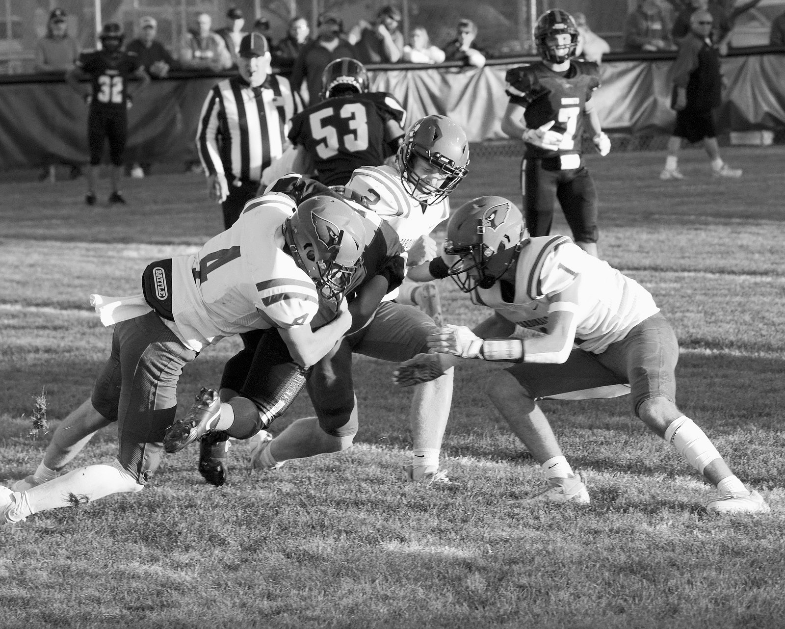 Sam Davis, Jayden Lee, and Jax Johnson tackle a Hornet player for a turnover in downs. Photo by Larry Stokke.