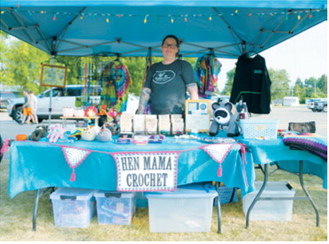 Hen Mama Crochet vendor displays colorful crocheted items, woven hot pads, beaded sun catchers and tie-dye clothing during the Walhalla Growers and Makers Market’s special night market Wednesday, Aug. 12. Photo by Larry Stokke