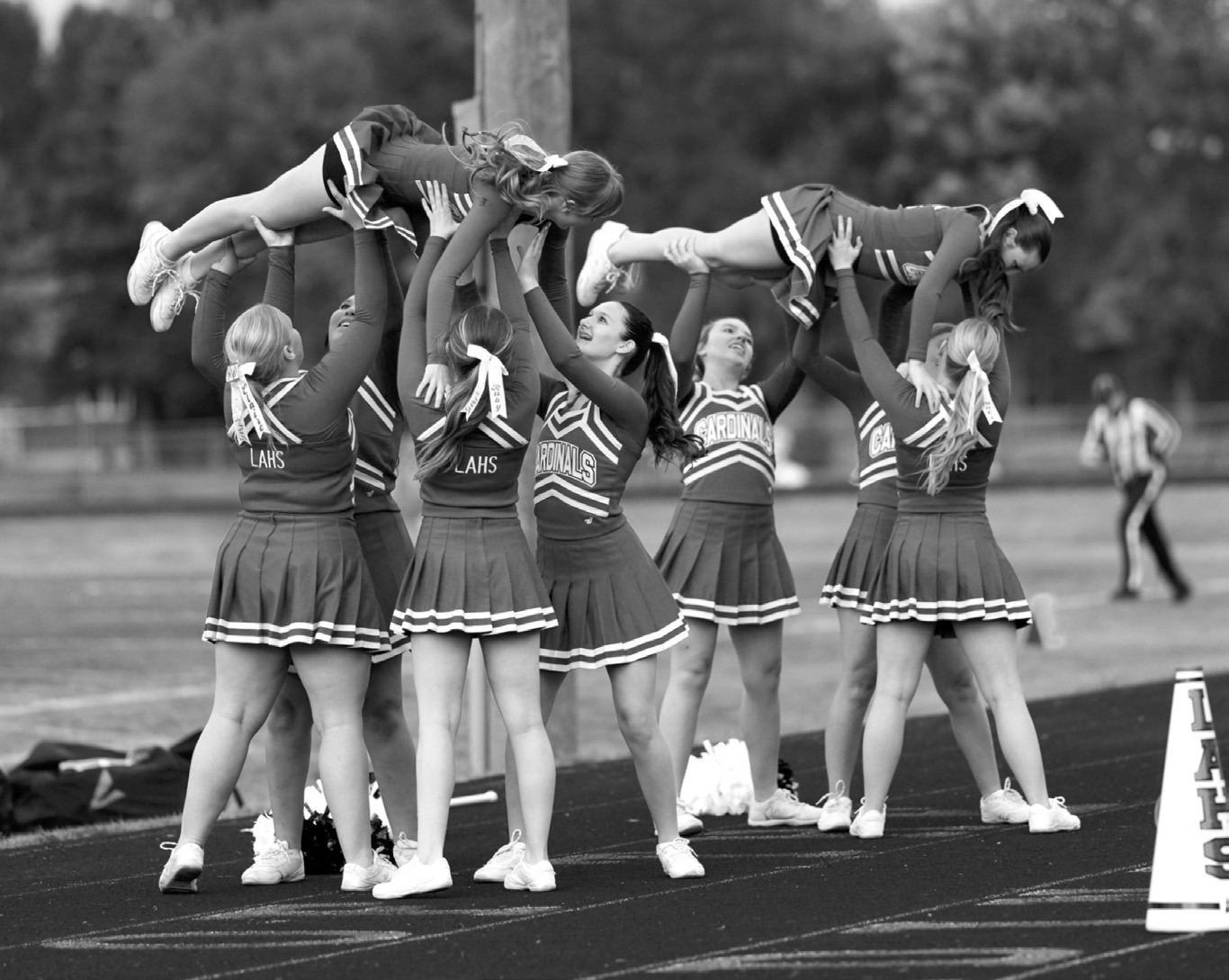 Cardinal cheerleaders lift their teammates during a sideline routine, bringing energy and school spirit to the field. Photo by Larry Stokke