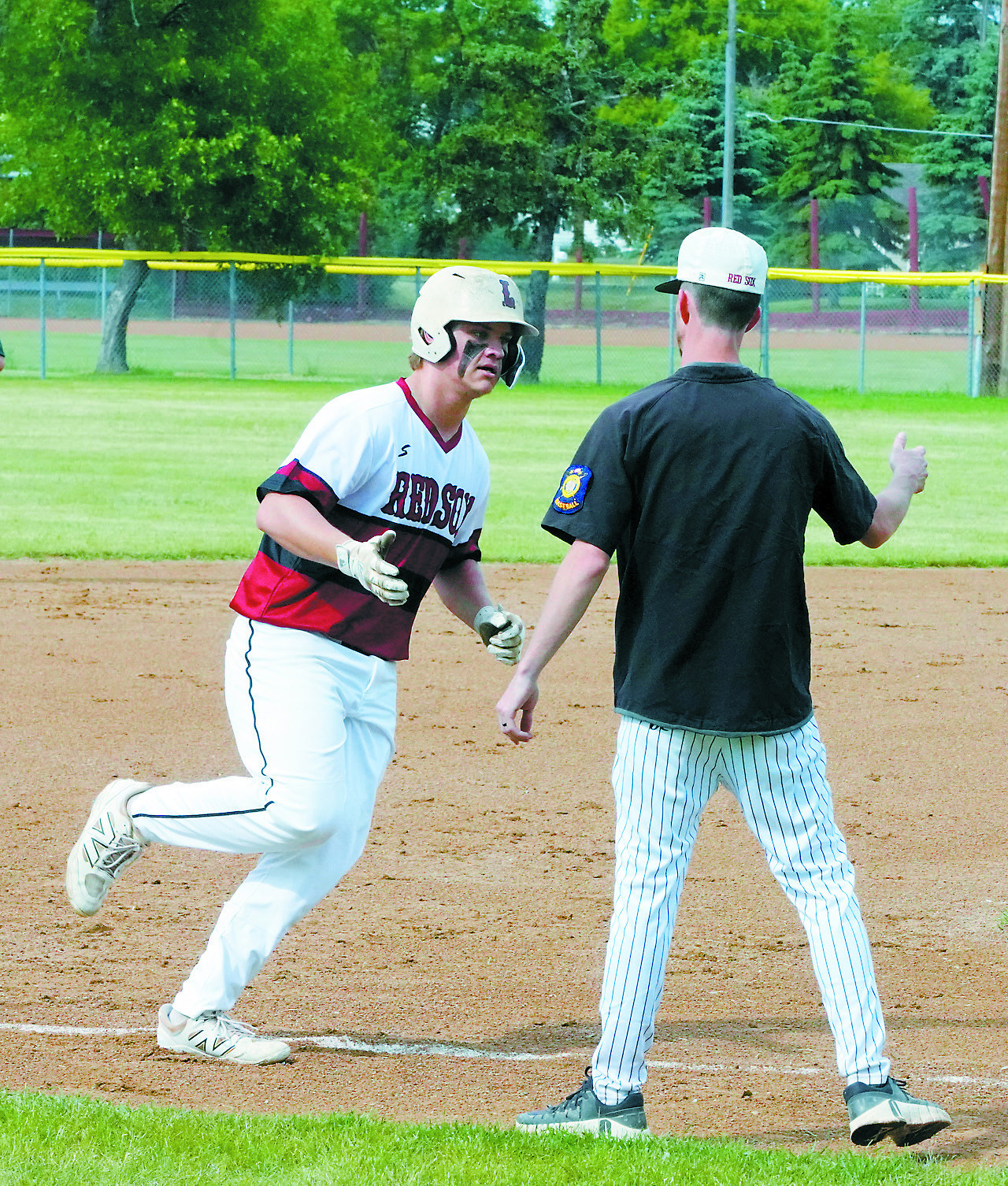 Coach Groth congratulates Theo Romfo on his home run hit against Thompson June 18 in Langdon. Photo by Larry Stokke.