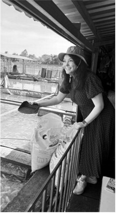 Billie Lentz of Perth tried her hand feeding fish at an aquaculture operation. ND Soybean Council photo