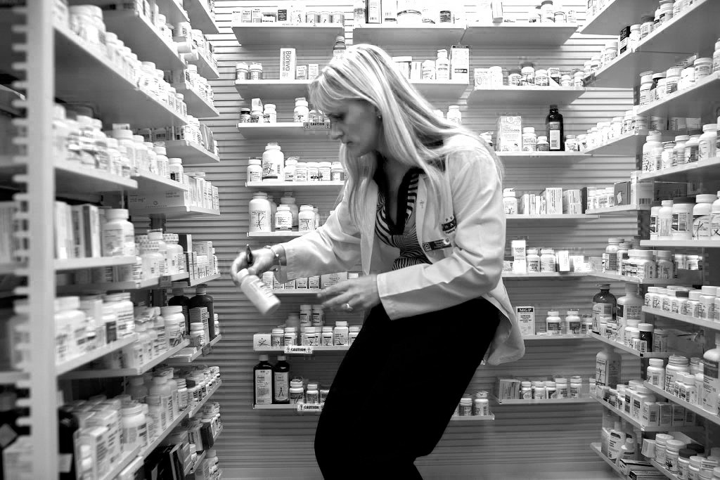 A pharmacy manager retrieves a bottle of antibiotics. (Photo by Joe Raedle/Getty Images)