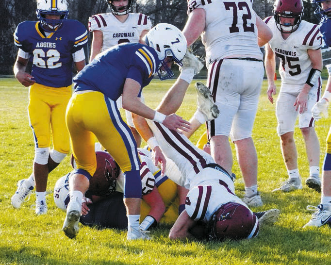 Landon Schneider takes down a Velva Aggie, allowing Sam Davis to leap over him and score for the Cards. Photo by Larry Stokke.