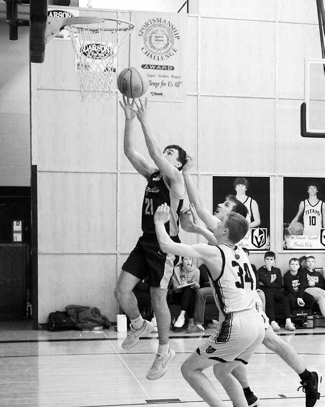 Brody Berg drives past two Titans and lays in a basket. Photo by Larry Stokke.