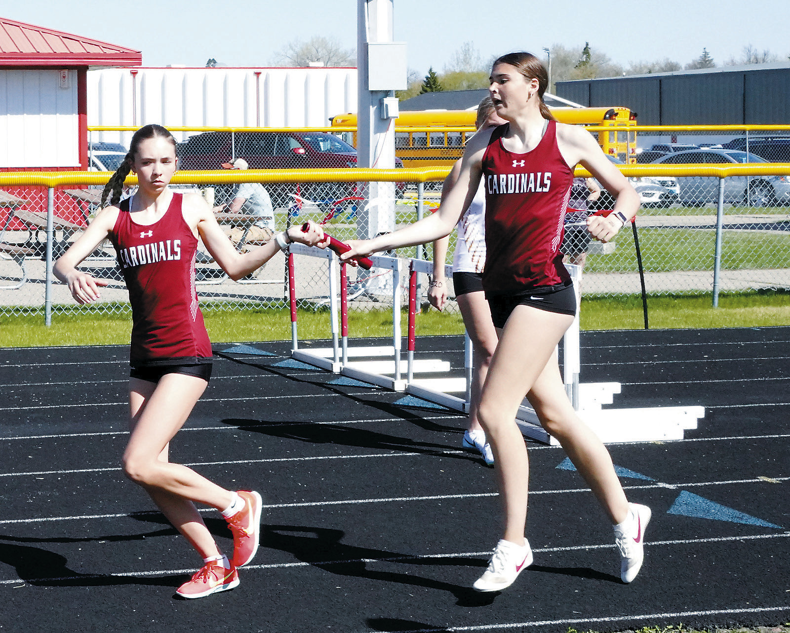 Taya Feist hands the baton to Olivia Lorenz who, along with Hallie Overby and Mya Swanson, placed first in the 4X800 relay on April 5. Photo by Larry Stokke.