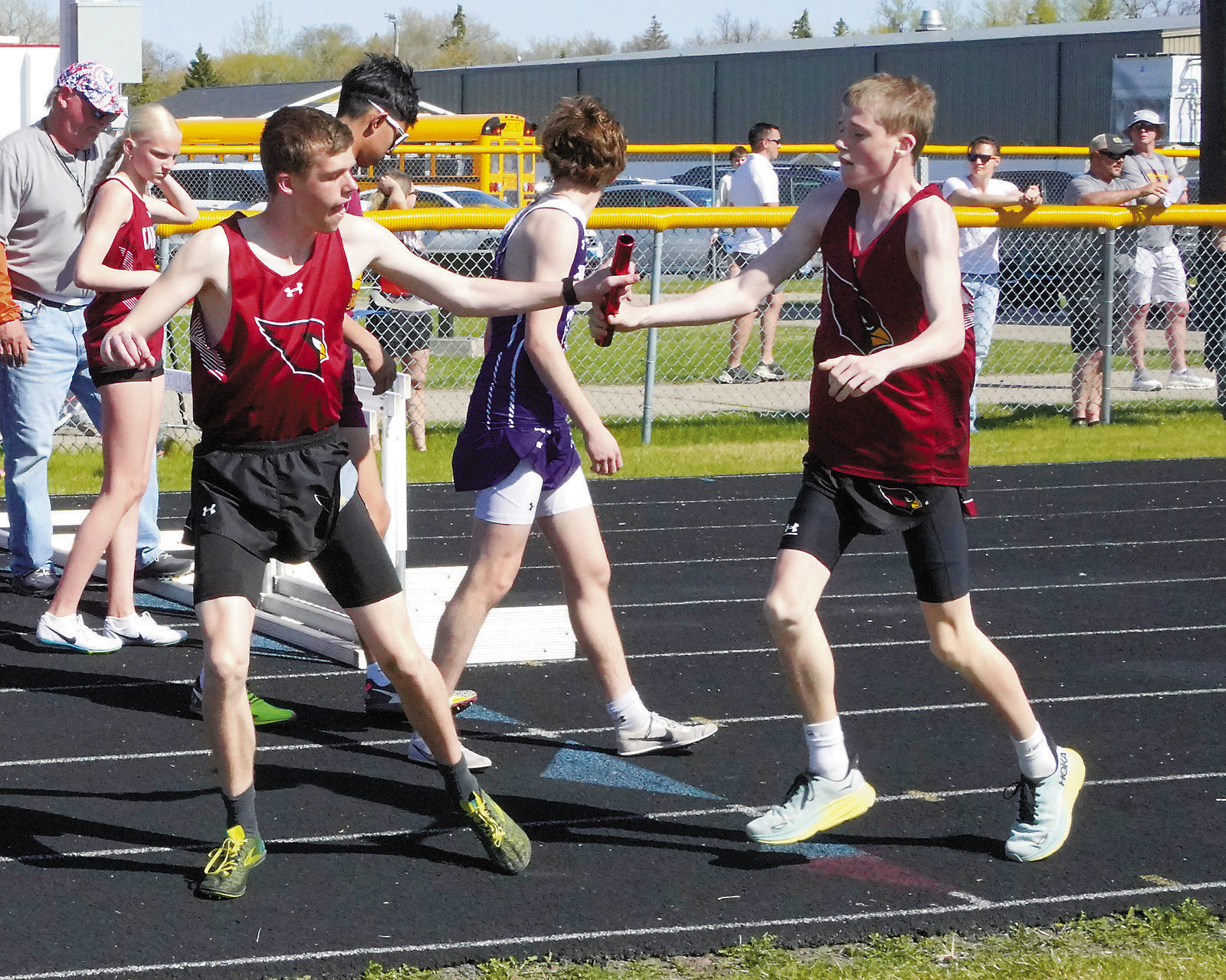 Kaleb Foster hands off the baton to Noah Foster who, along with Jayden Lee and Tyler Borgen, took first place in the 4x800 relay. Photo by Larry Stokke.