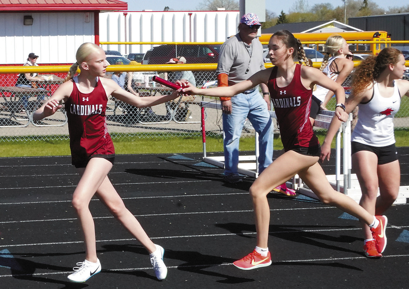 Olivia Lorenz hands the baton to Mya Swanson in Devils Lake on April 5. Photo by Larry Stokke.