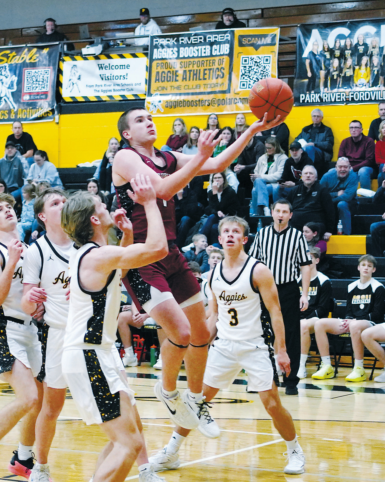 FM Bank's Player of the Game Eastyn Schaefer drives between four Aggie players and drops in a left-handed layup, finishing the game with 20 points. Photo by Larry Stokke.