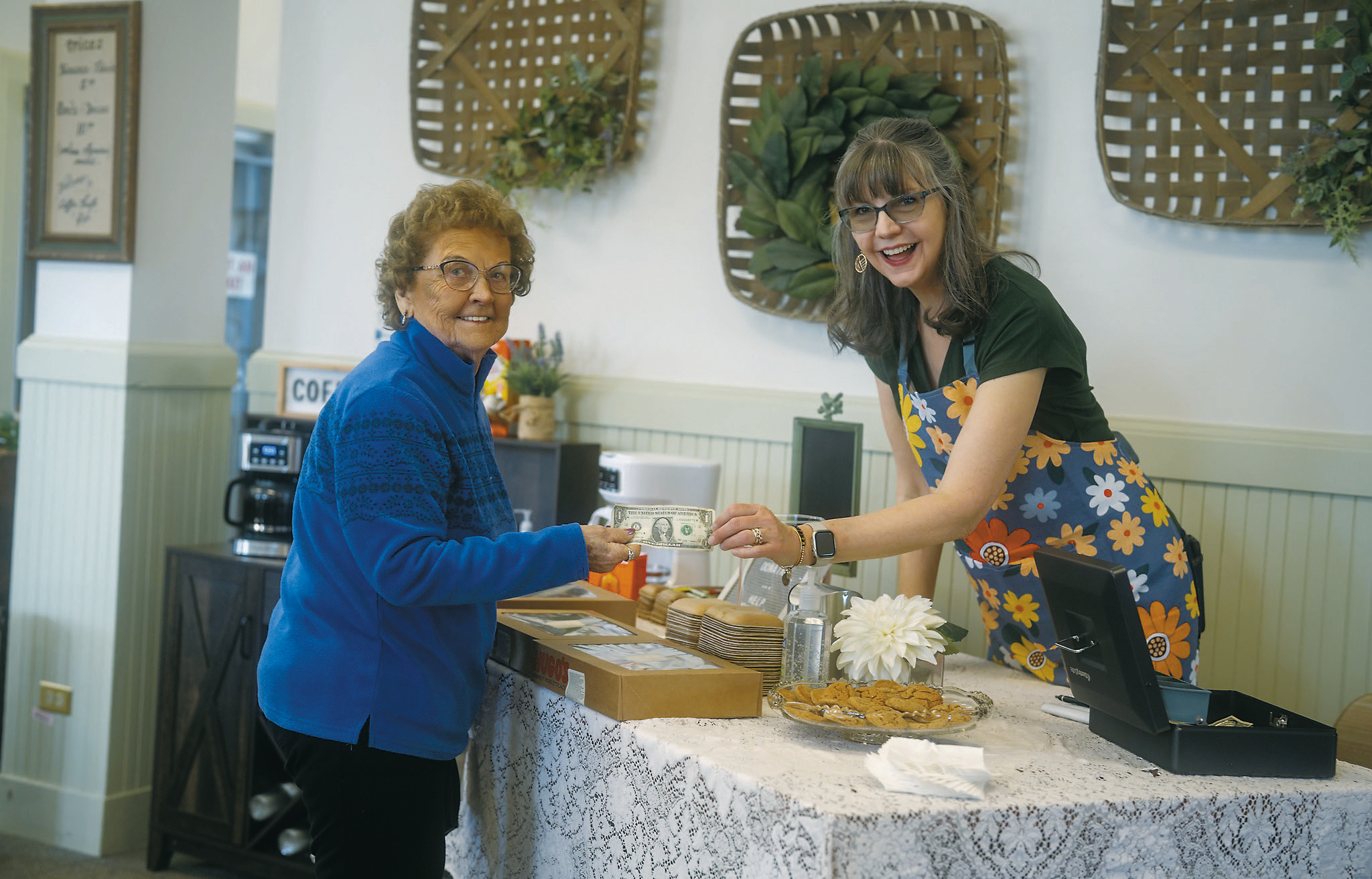 Mary Lou Swiscoski receives her first dollar bill from Gladys Kemnitz at the grand opening of Coffee, Thrift, and Gift. Photo by Jesus Ramos.